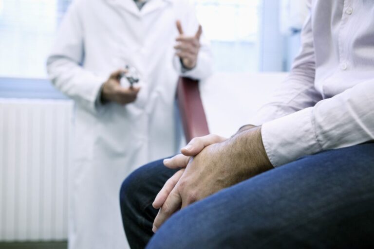 A physician consults with their patient in an exam room.