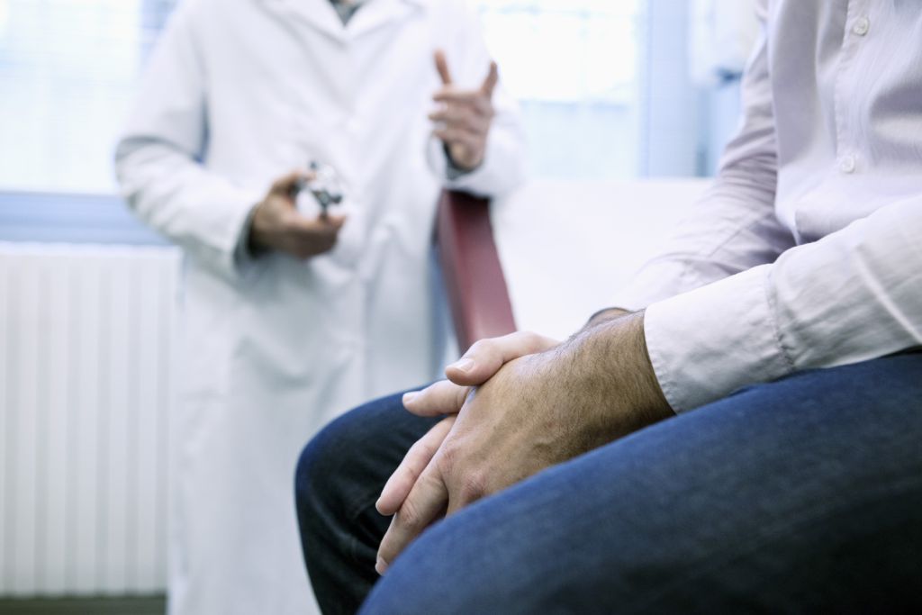 A physician consults with their patient in an exam room.