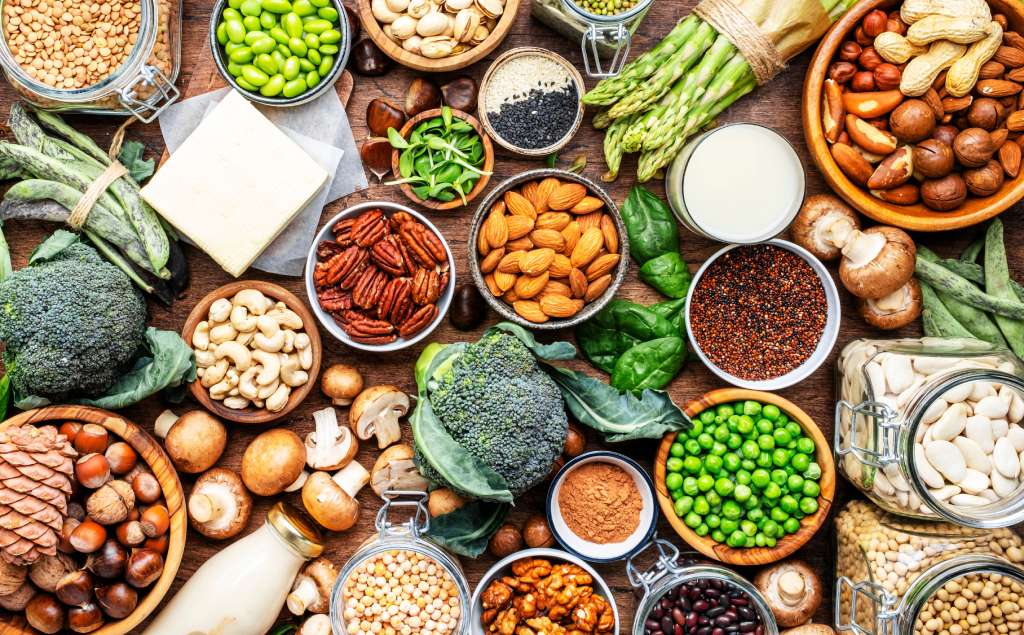 Various grains, vegetables, and nuts sit on a wooden table.