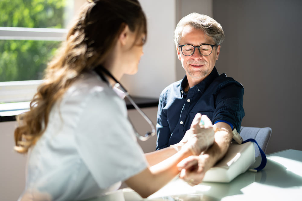 A Man Has His Blood Drawn By A Nurse In An Exam Room